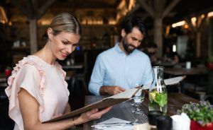 Happy couple sitting indoors in restaurant, looking at menu