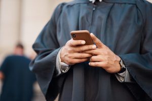 Lawyer, hands and cellphone with judge for justice at courtroom in city for communication or resear