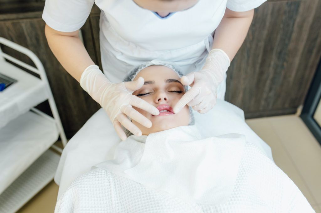doctor's hands in white gloves touch the lips, plastic surgery, contour lip surgery